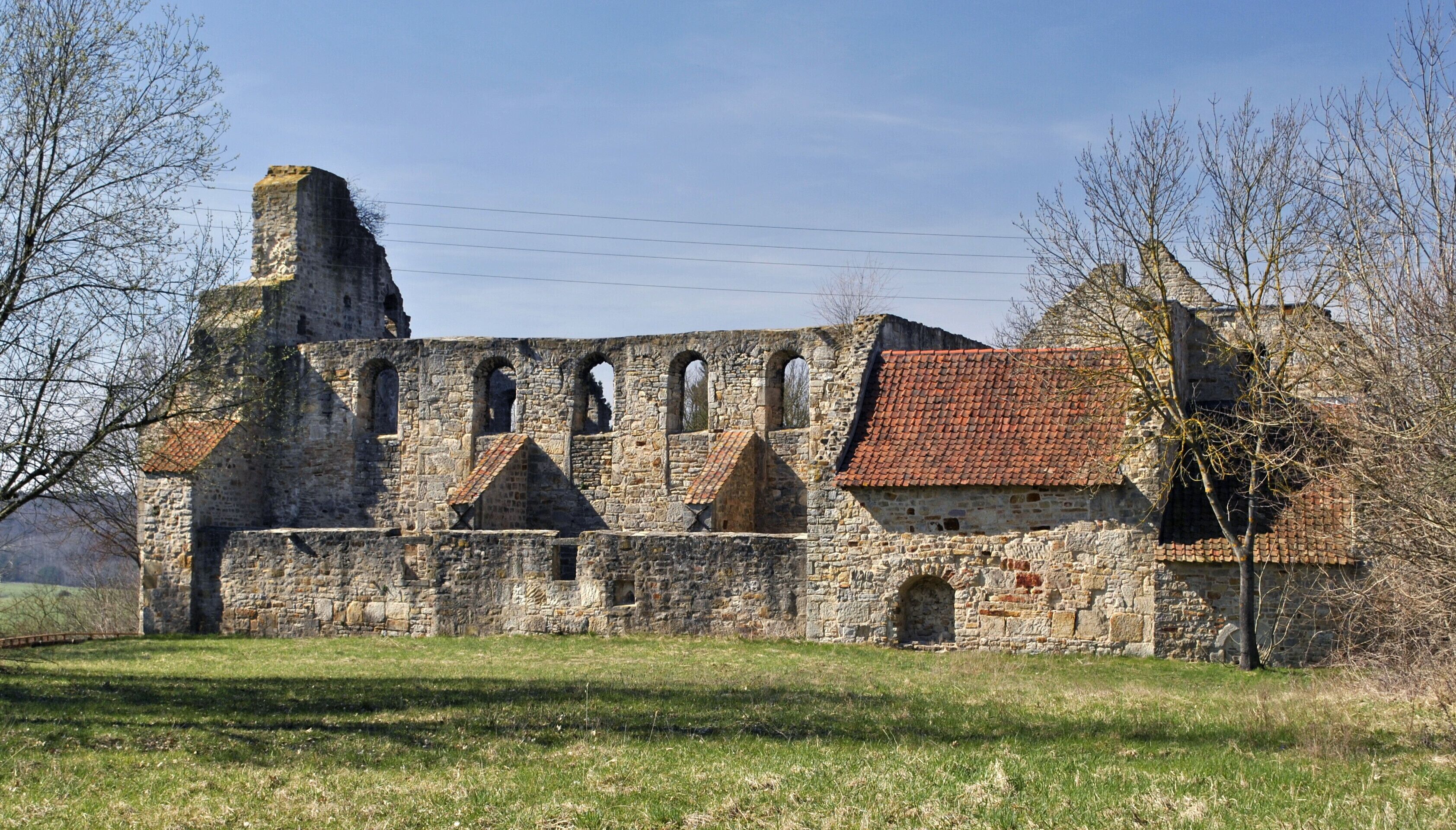 An ancient stone building with arched windows and a red-tiled roof.