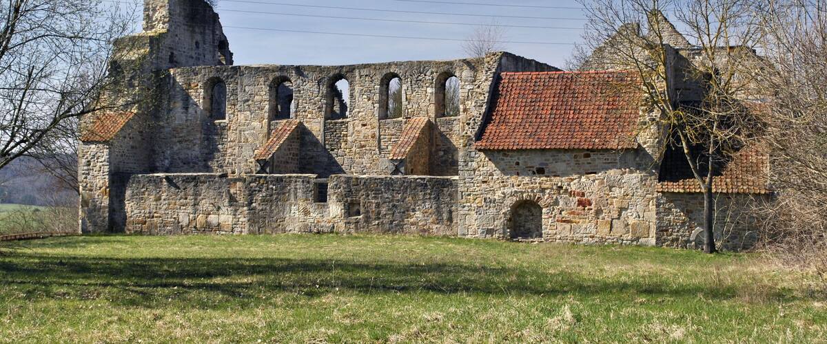 An ancient stone building with arched windows and a red-tiled roof.
