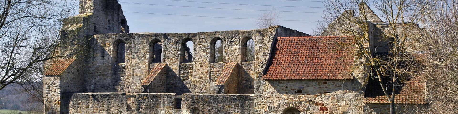 An ancient stone building with arched windows and a red-tiled roof.