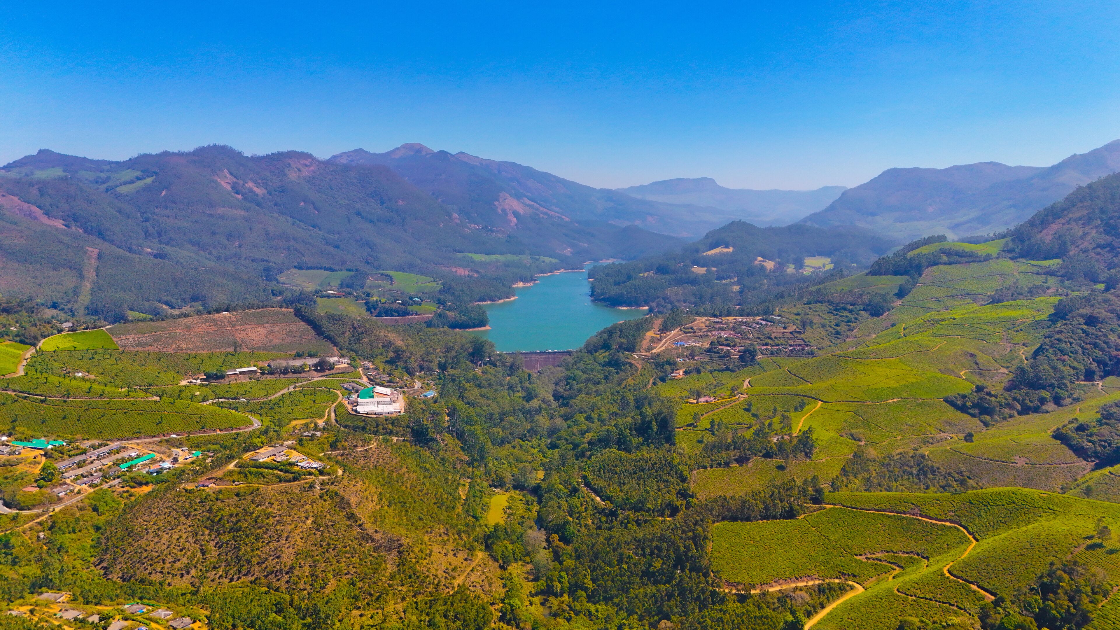 A mountainous landscape with a lake, terraced fields, and a small settlement.