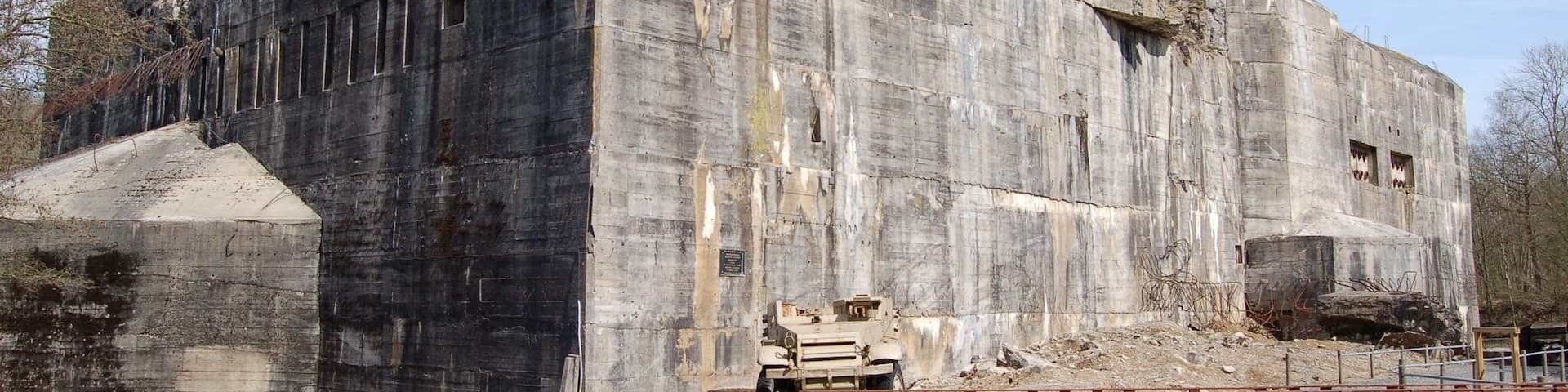 A large, weathered concrete building with multiple windows and a ramp leading up to it.