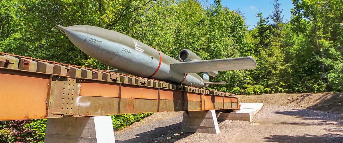 A missile on a display platform with trees in the background.