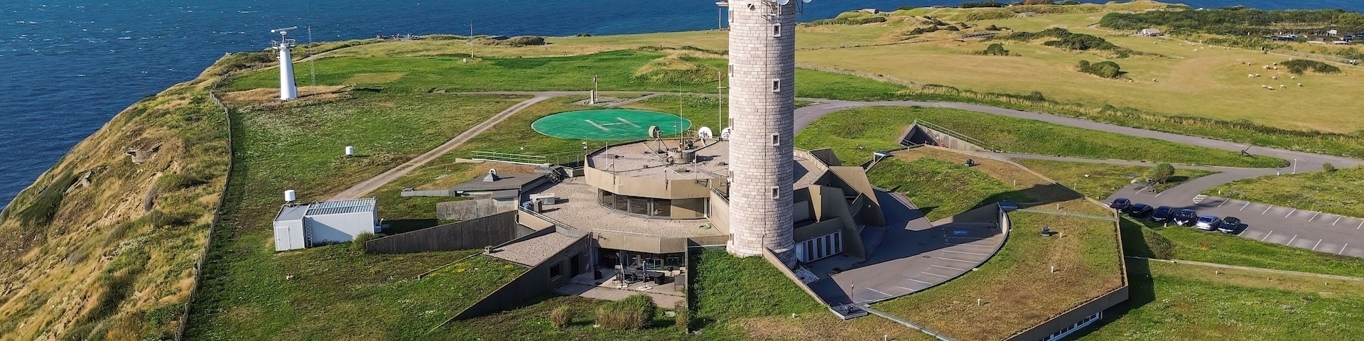 Un faro sobre una colina cubierta de hierba, con vista despejada al océano.