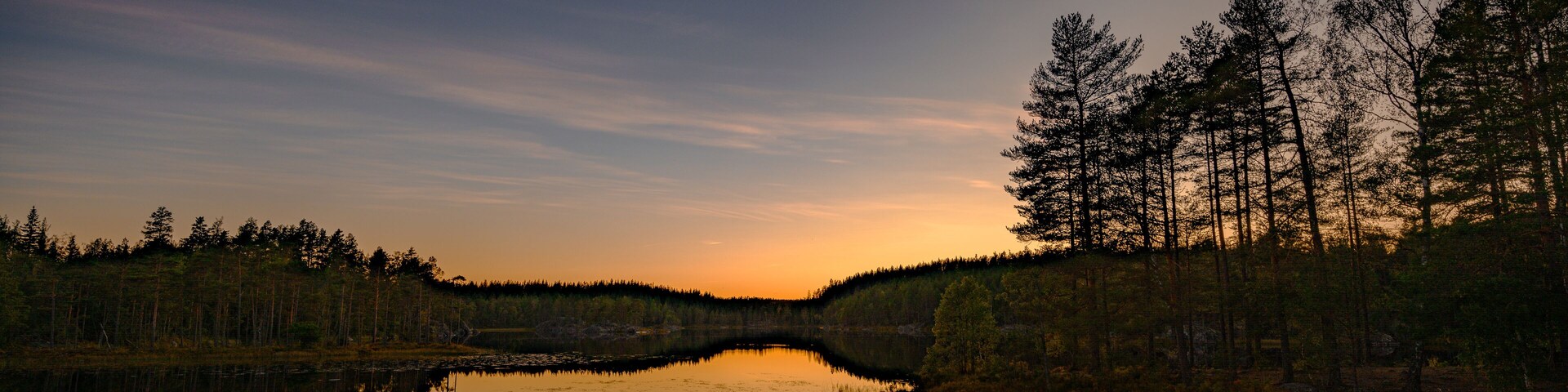 Un lago tranquilo que refleja árboles y un cielo al atardecer.