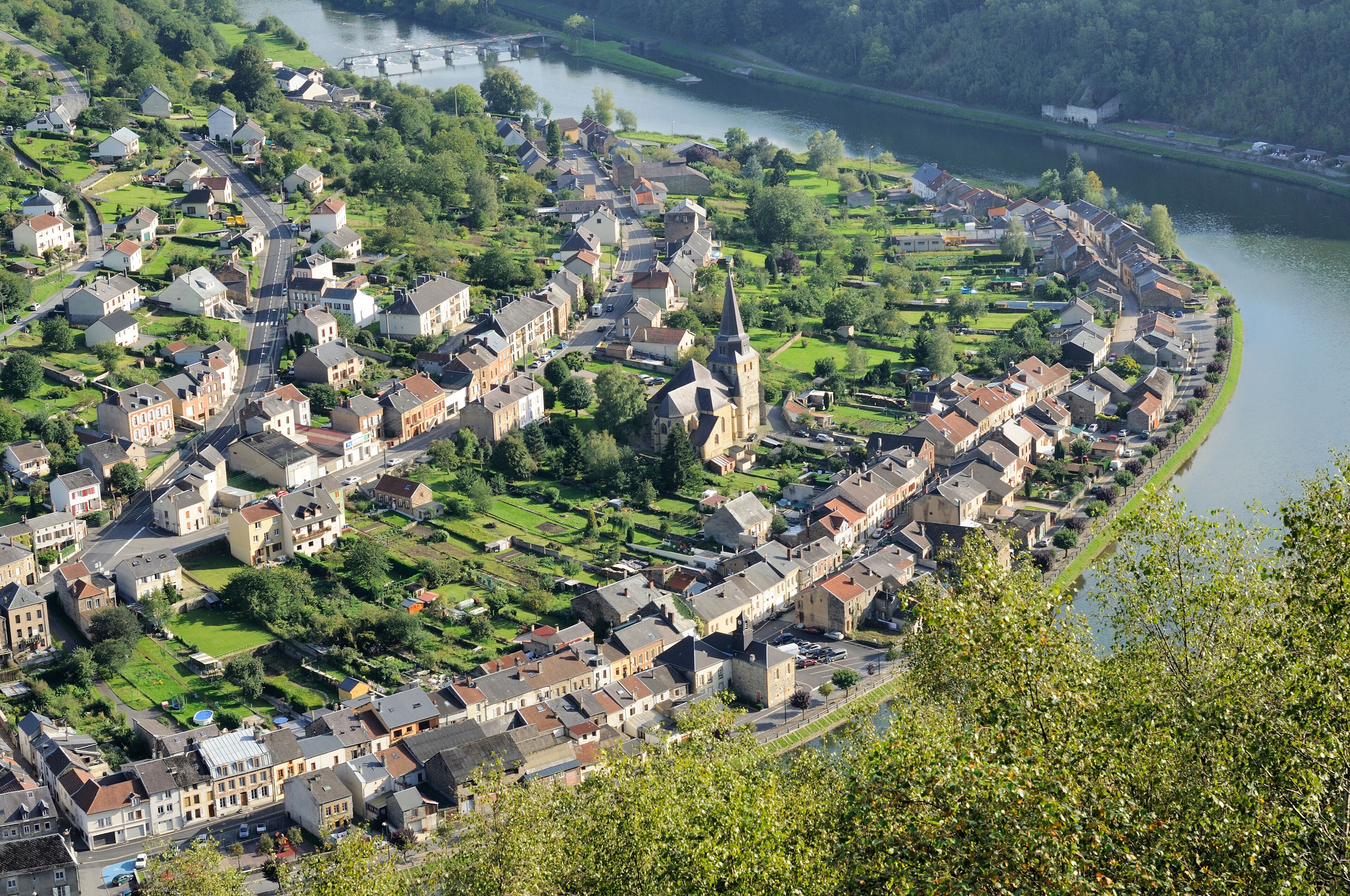 A riverside town with historic buildings, a prominent church steeple, and lush green parks.