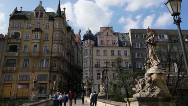 Una calle adoquinada flanqueada por edificios históricos y estatuas.