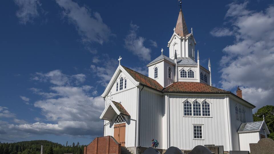 A white church with a tall steeple and a red-tiled roof.