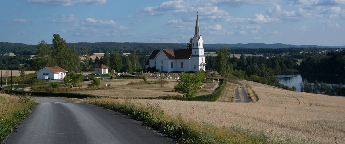 A rural landscape with a church, a road, and a body of water.