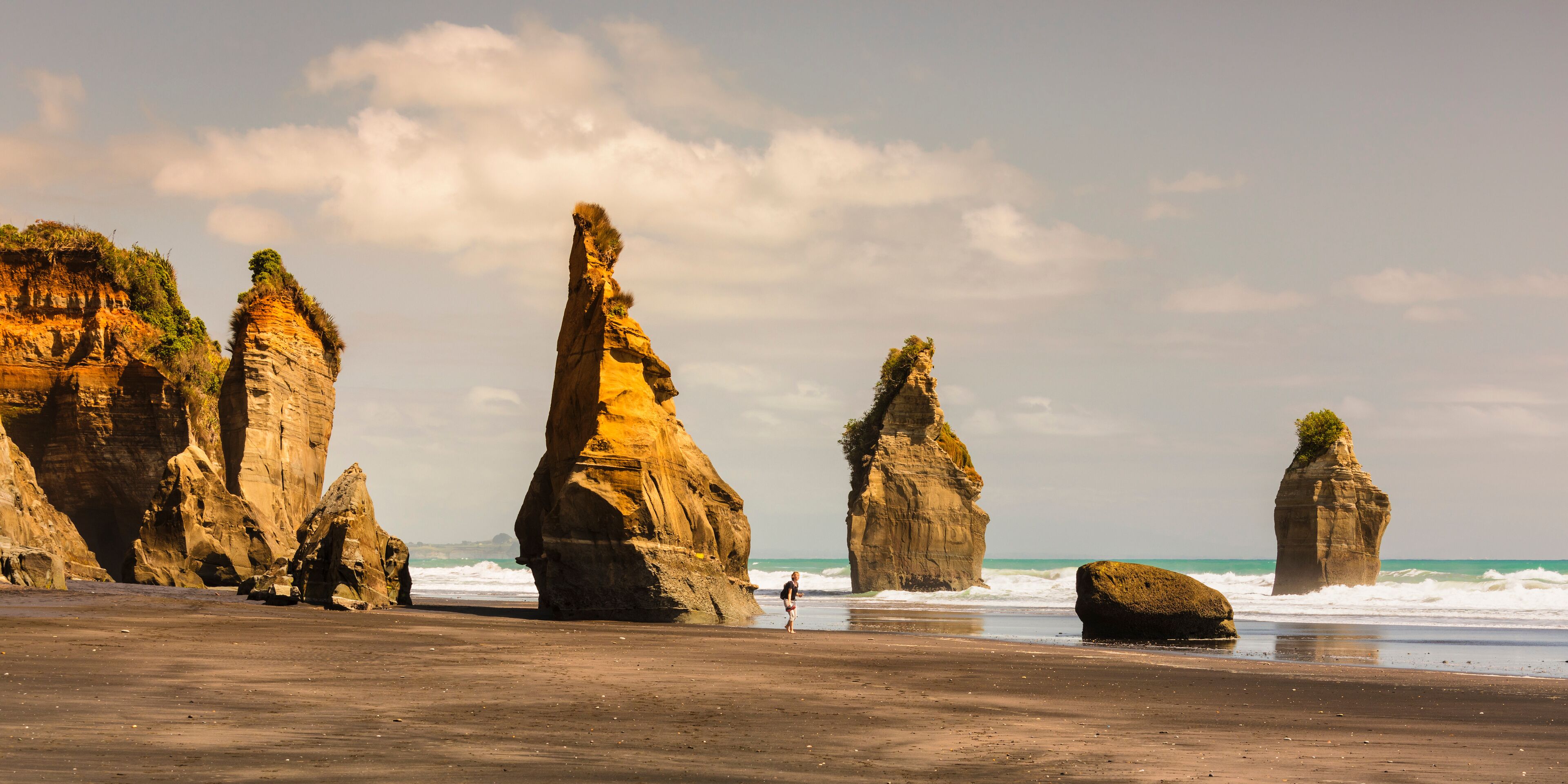 A beach with prominent rock formations and the ocean in the background.