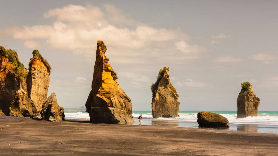 A beach with prominent rock formations and the ocean in the background.