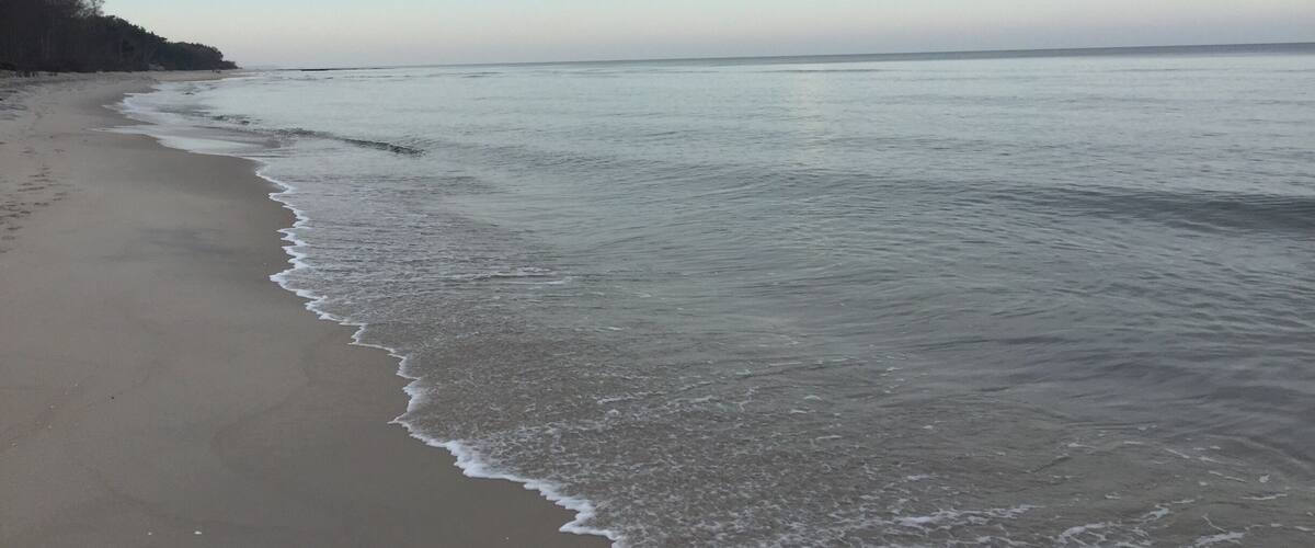A beach with gentle waves and a clear sky.
