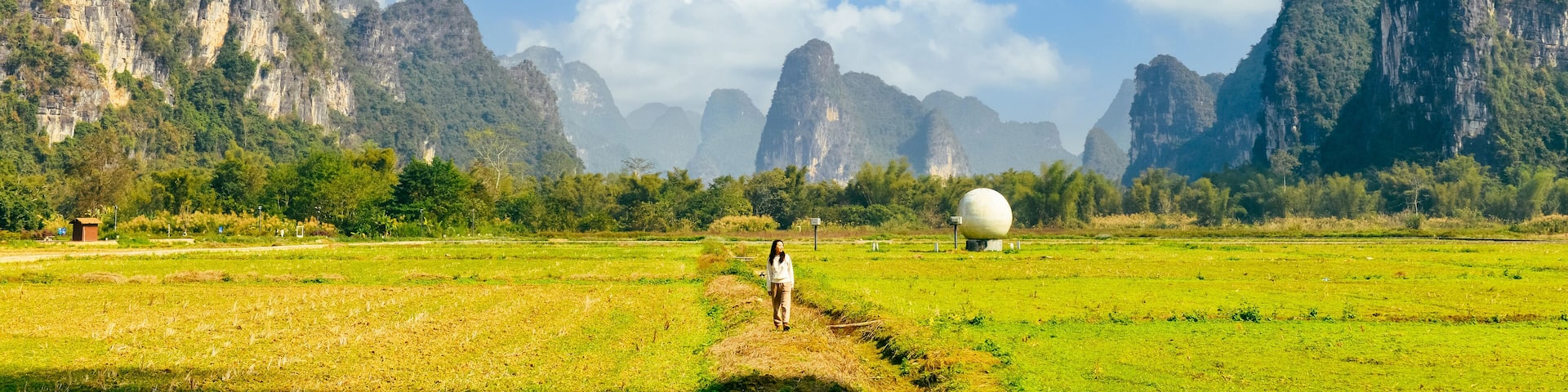 One Asian woman enjoying beautiful rural landscape surrounded by Karst mountains in winter at Mingshi Village (Mingshi Tianyuan) in Daxin County, Chongzuo city, Guangxi, China