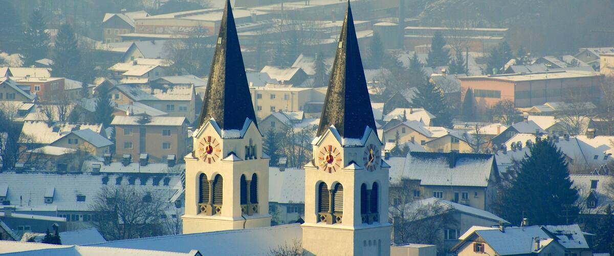 A church with two spires and a clock tower in a snowy town.