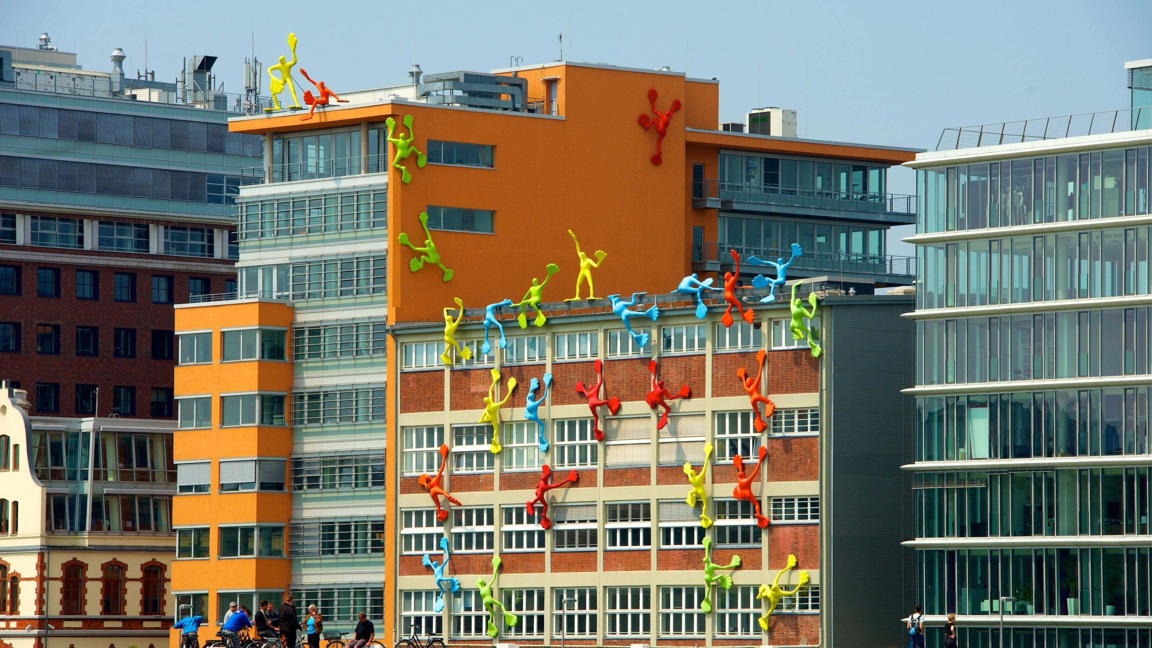 A modern building with colorful sculptures of people climbing and dancing on its facade.