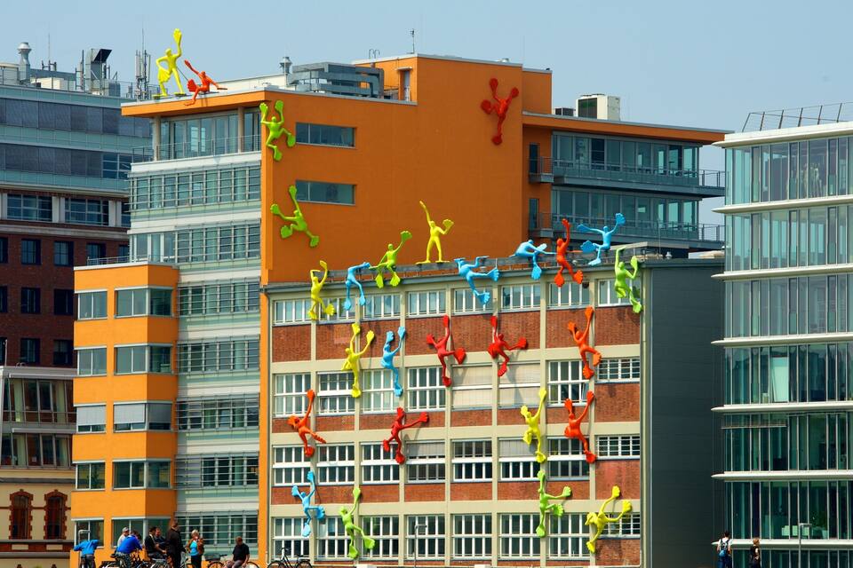 A modern building with colorful sculptures of people climbing and dancing on its facade.