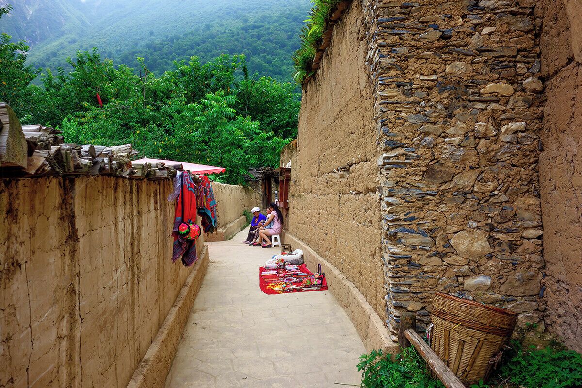 A narrow alleyway with stone walls, a red umbrella, and a basket.