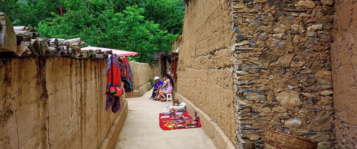 A narrow alleyway with stone walls, a red umbrella, and a basket.