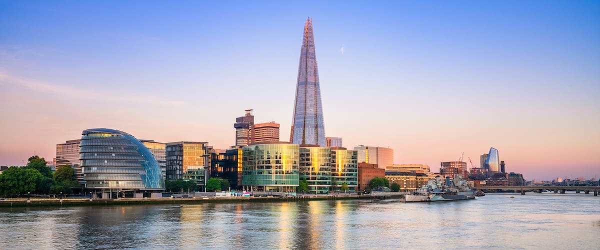 A city skyline with modern architecture, including a prominent skyscraper, by a river.