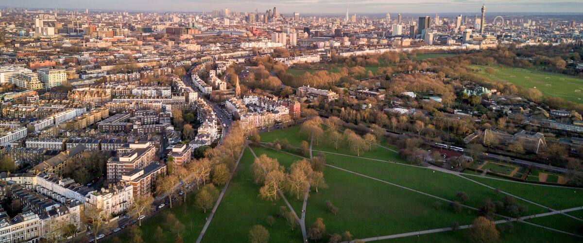 Vista aérea de un paisaje urbano con edificios densos, un amplio parque y una torre destacada.