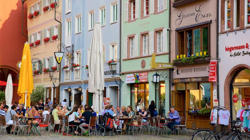 Un cafè a l'aire lliure ple de vida, amb gent menjant i xerrant.