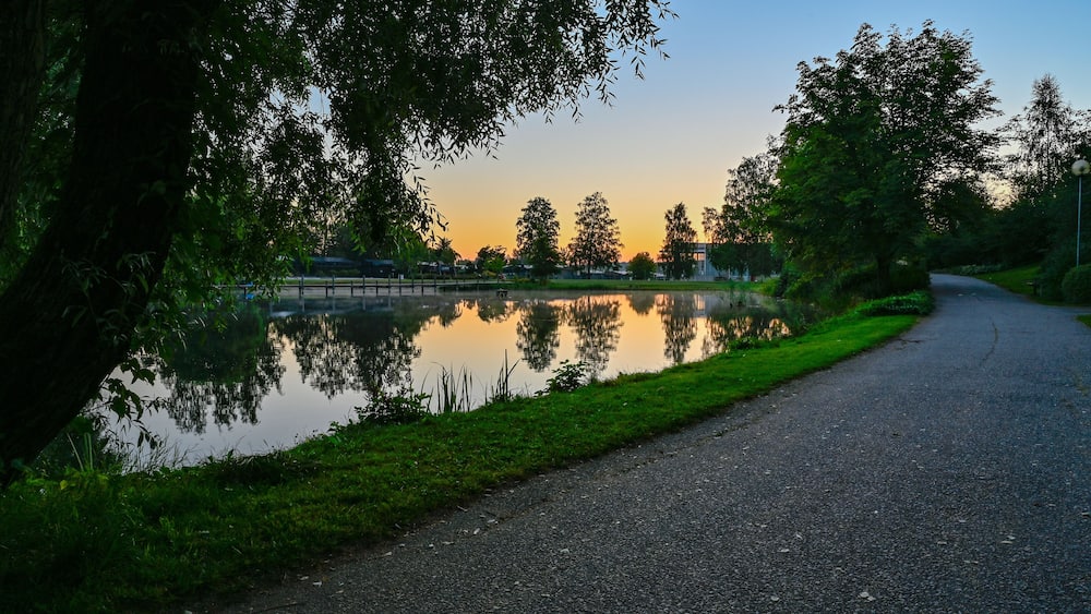 A serene lakeside path with a sunset in the background.