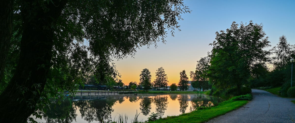 A serene lakeside path with a sunset in the background.