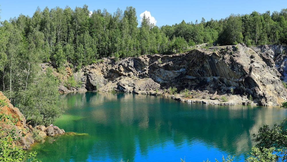 Un lac d’un bleu profond, entouré d’un paysage rocheux et d’une forêt dense.