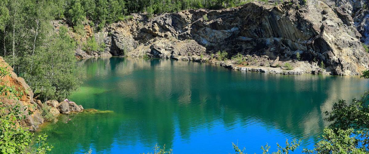 A clear blue lake surrounded by rocky terrain and dense forest.
