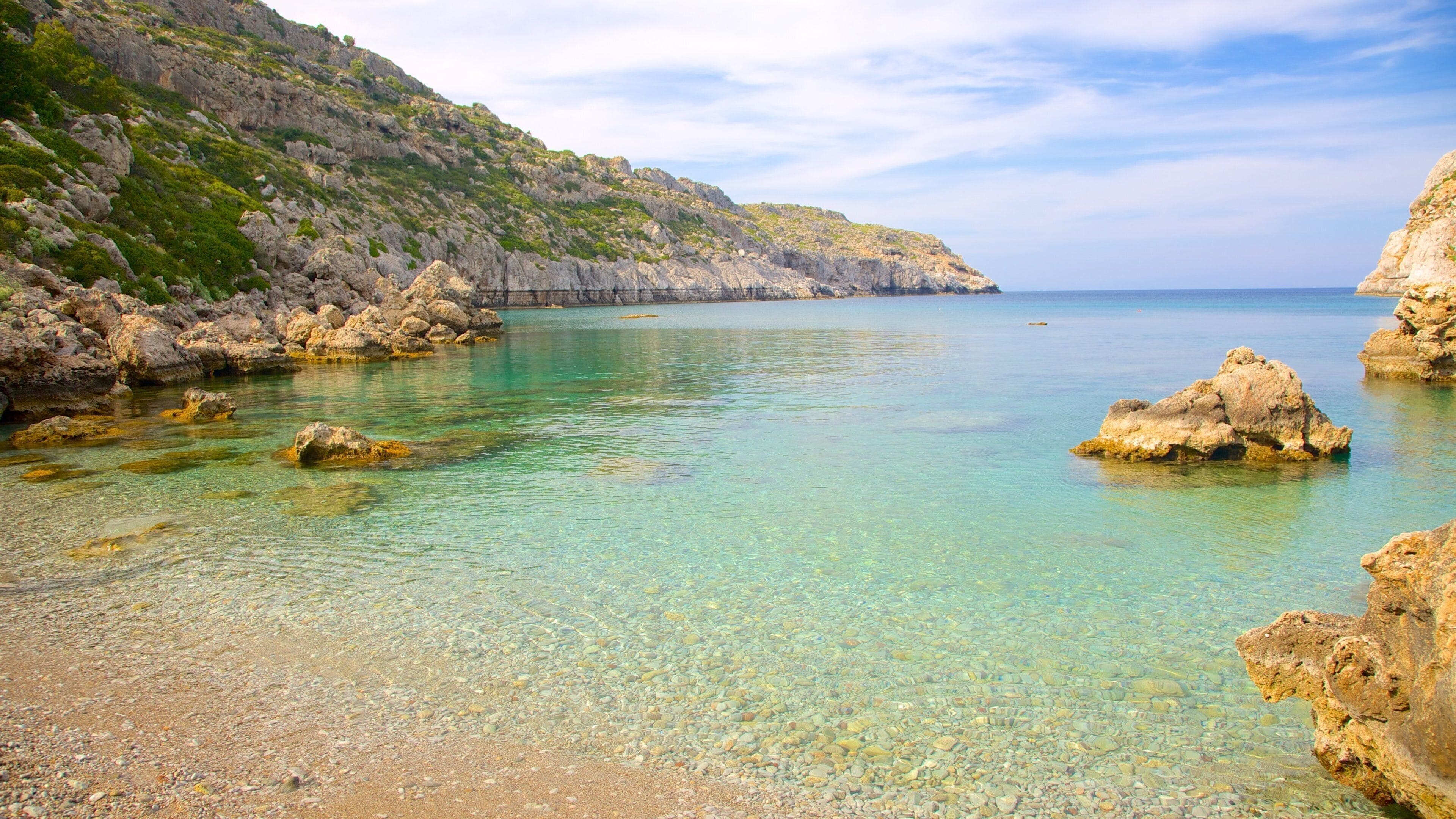Anthony Quinn Bay showing a bay or harbor, rugged coastline and a pebble beach
