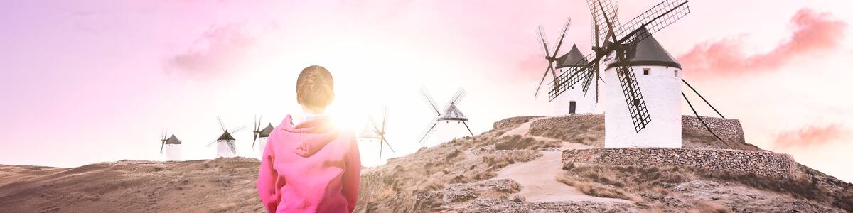 Spain Consuegra - Tourist woman looking at Don Quixote windmills. Female traveler on vacation visiting spanish landmarks.
