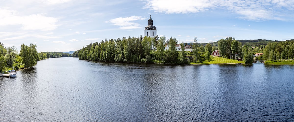 A lake with a church on an island, surrounded by trees and houses.