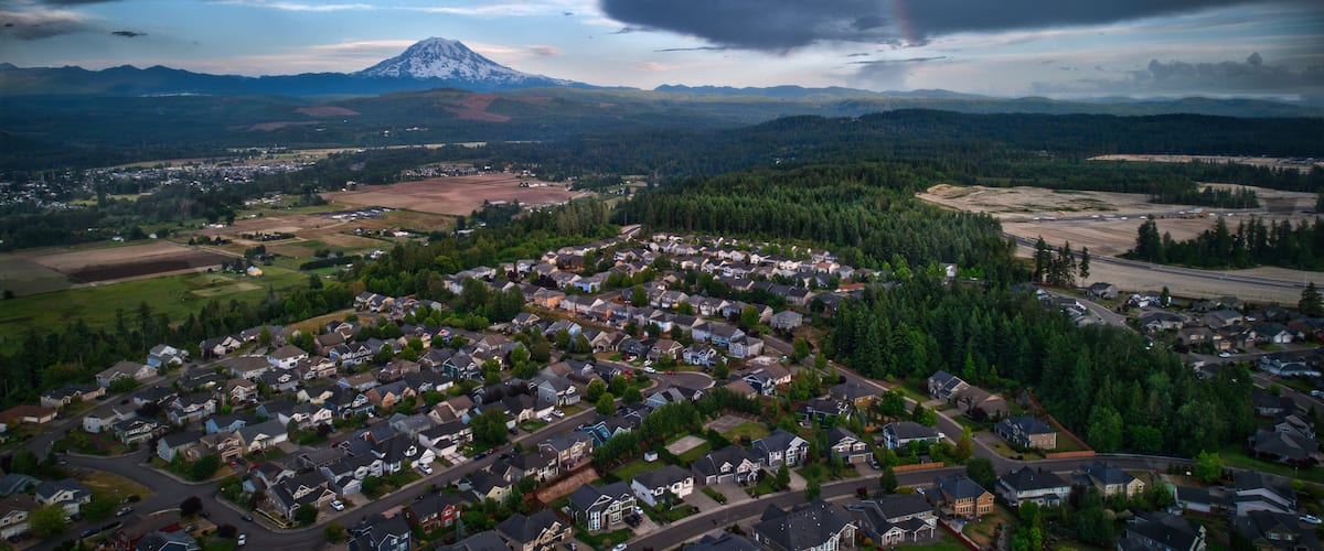 A residential area with houses, roads, and a mountain in the background.