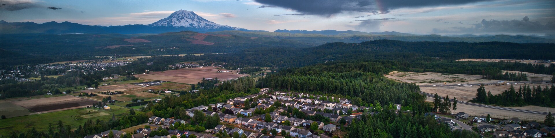 A residential area with houses, roads, and a mountain in the background.