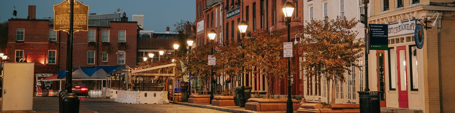 A historic downtown street at dusk with vintage street lamps, brick buildings, and a sign for 'FELSH POINT'.