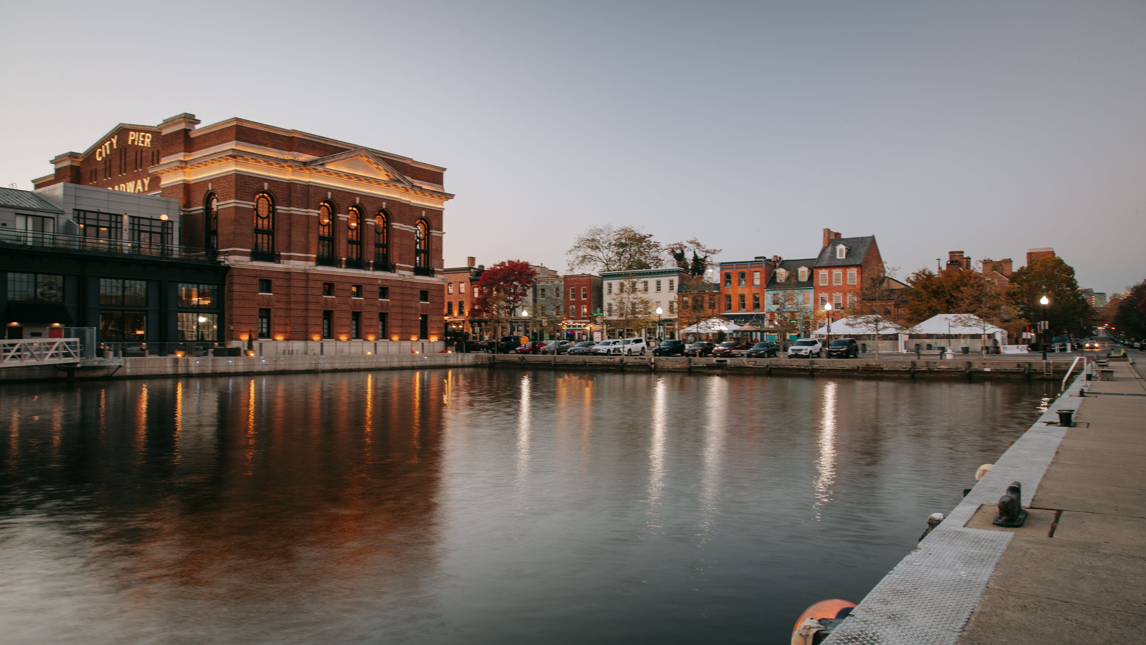 A riverside cityscape with historic buildings, including a prominent brick building with 'City Pier' signage.