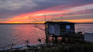 A wooden pier extending into a body of water during sunset with a colorful sky.