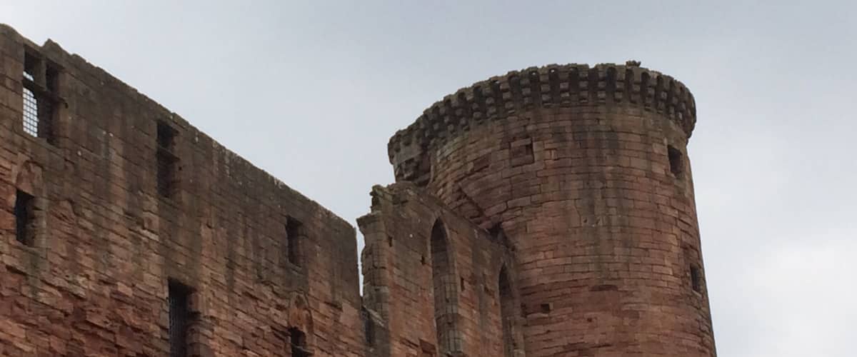 A large, historic brick castle with a tall, cylindrical tower.