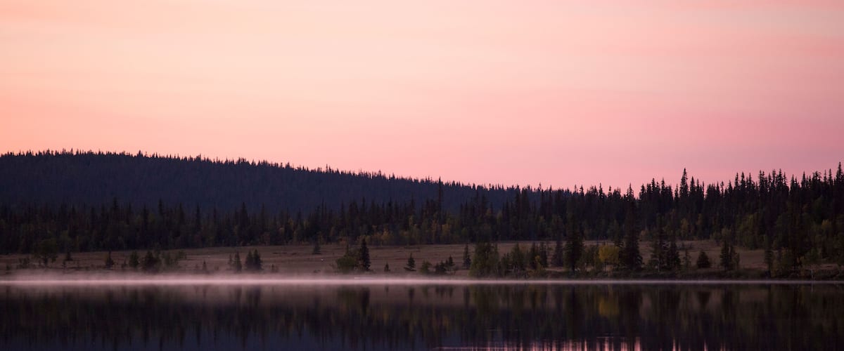 A calm lake with a forested hill in the background.