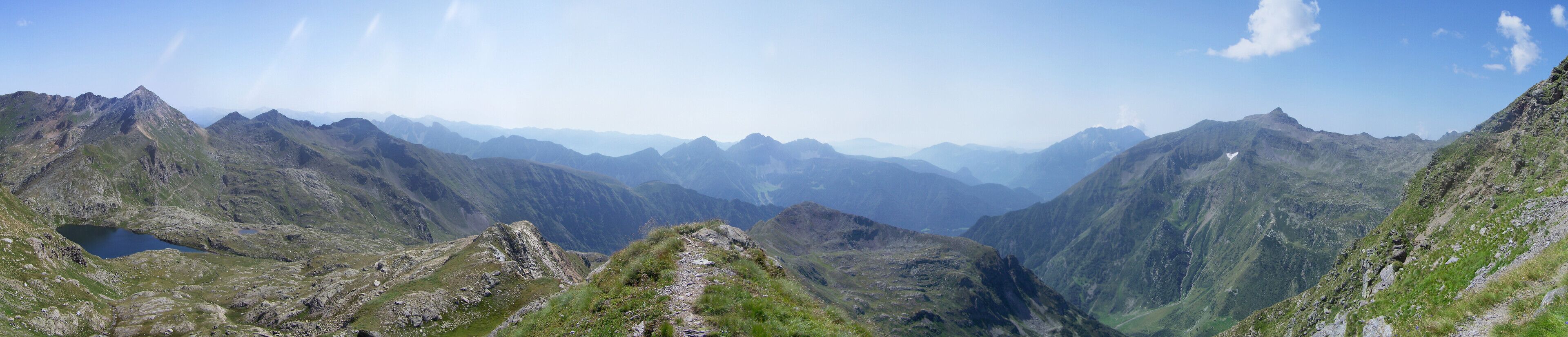 A mountainous landscape with a valley, rocky terrain, and a small lake.