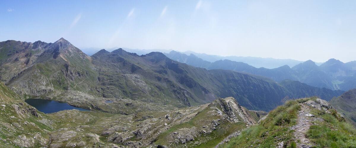 A mountainous landscape with a valley, rocky terrain, and a small lake.