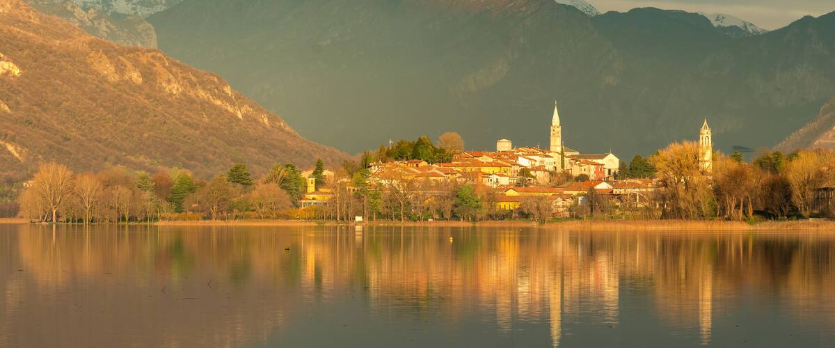 small town reflecting on a lake at sunset with mountains in the background