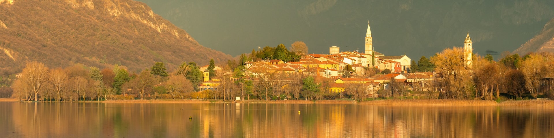small town reflecting on a lake at sunset with mountains in the background