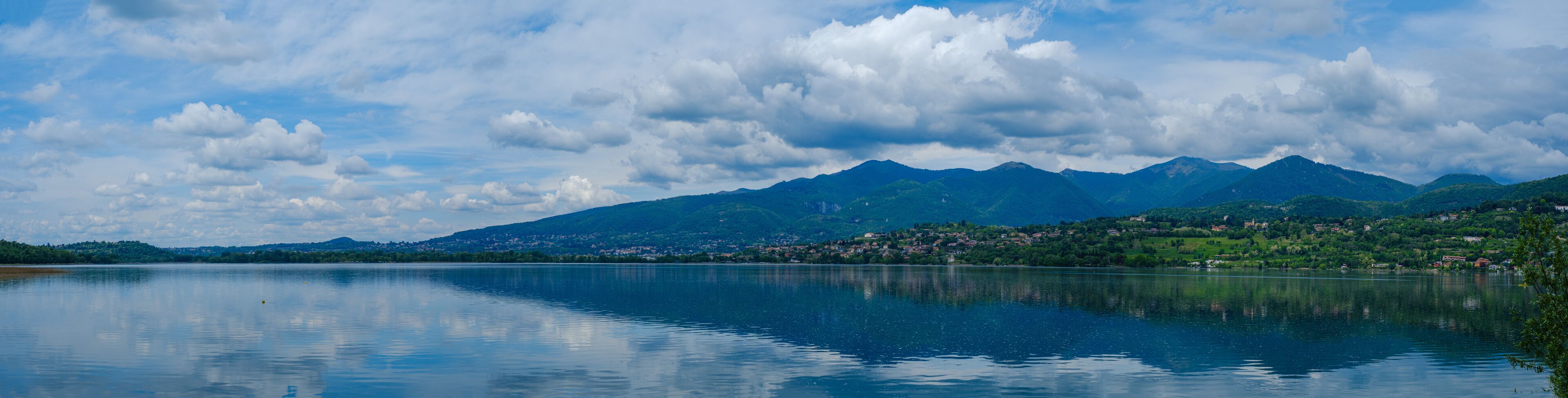 A calm lake with mountains in the background and a town on the right.