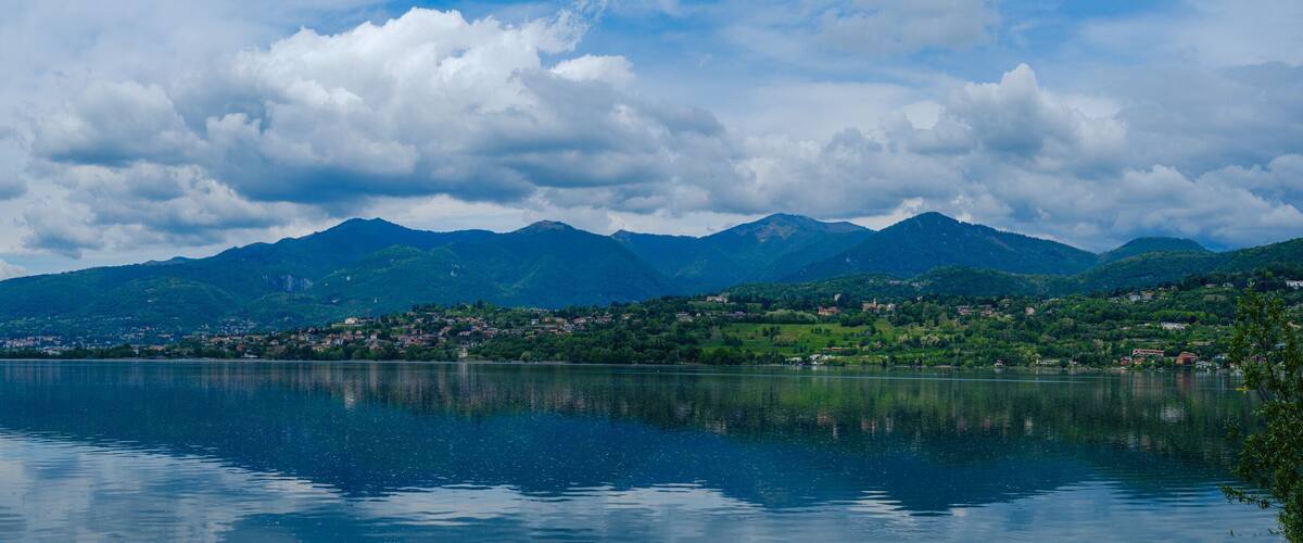 A calm lake with mountains in the background and a town on the right.