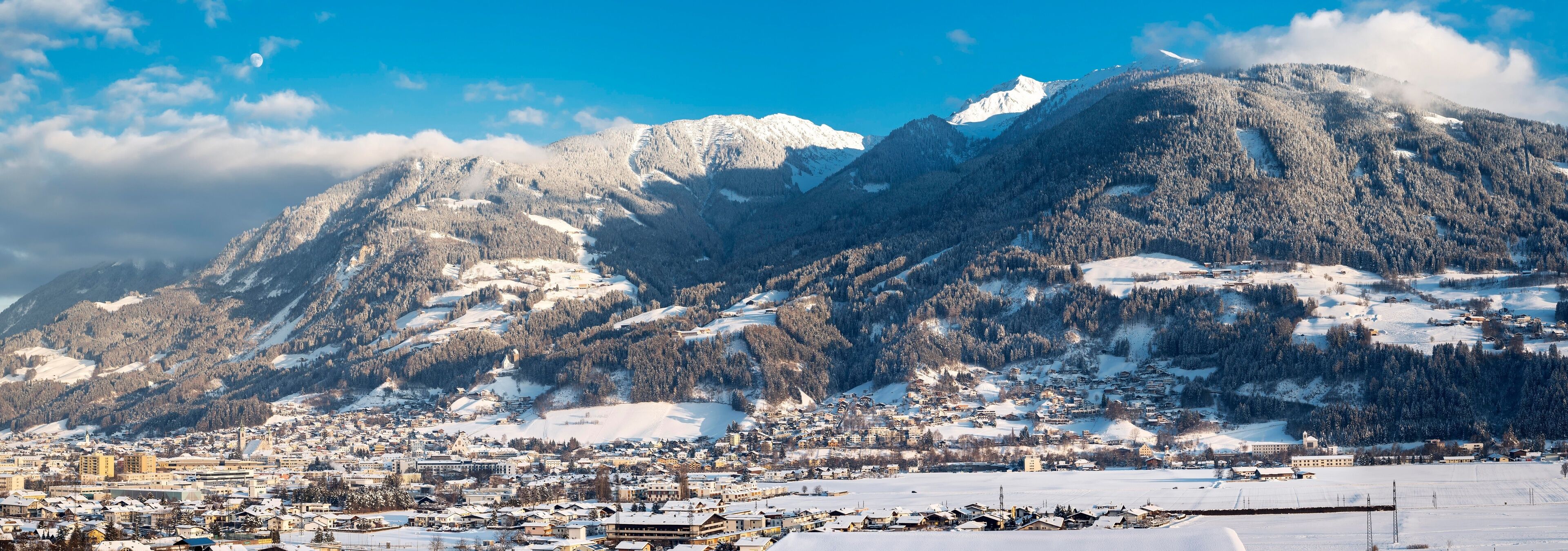 Cordilheira coberta de neve com uma cidade aos seus pés.