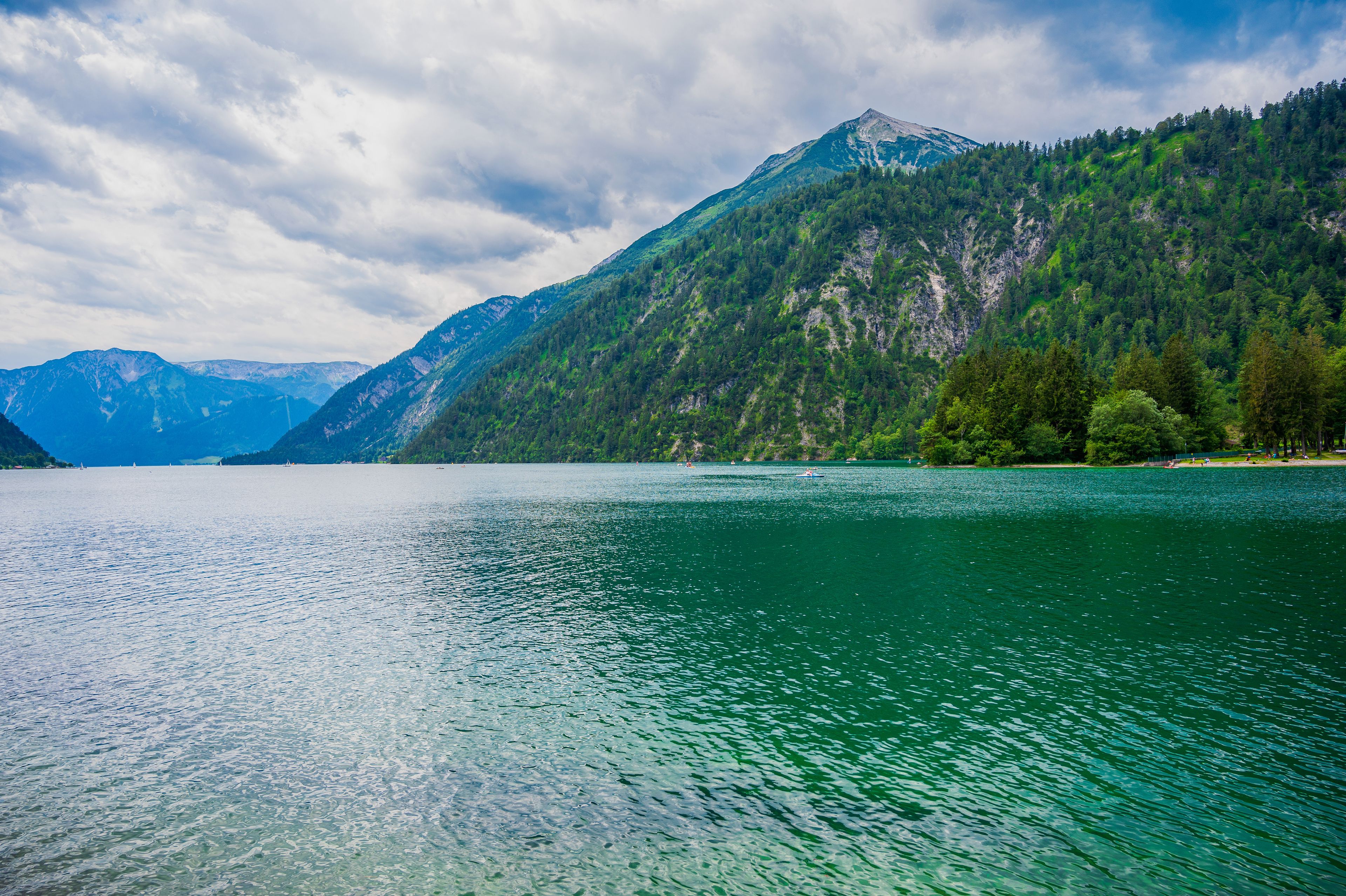 A calm lake surrounded by mountains and dense forests.