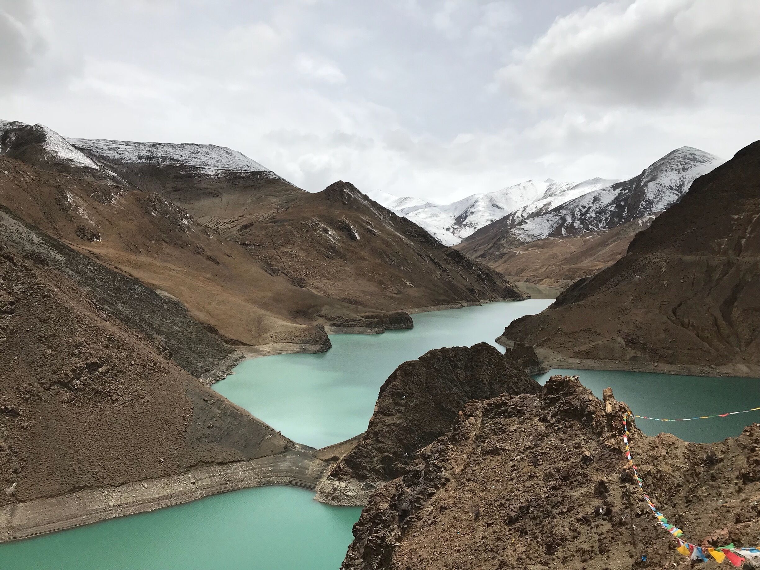 A turquoise lake surrounded by rugged mountains with snow-capped peaks.