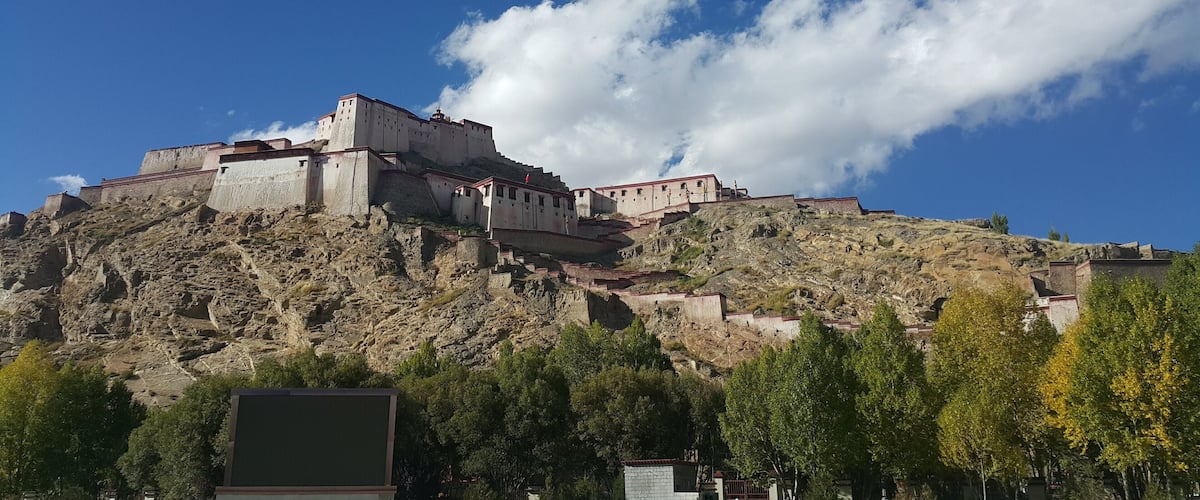 A large fortress-like structure on a hill with a clear blue sky and scattered clouds.