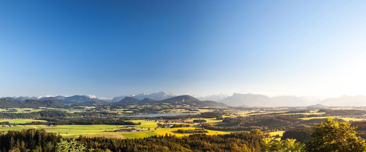 A mountainous landscape with a town nestled in the valley, surrounded by forests and fields.