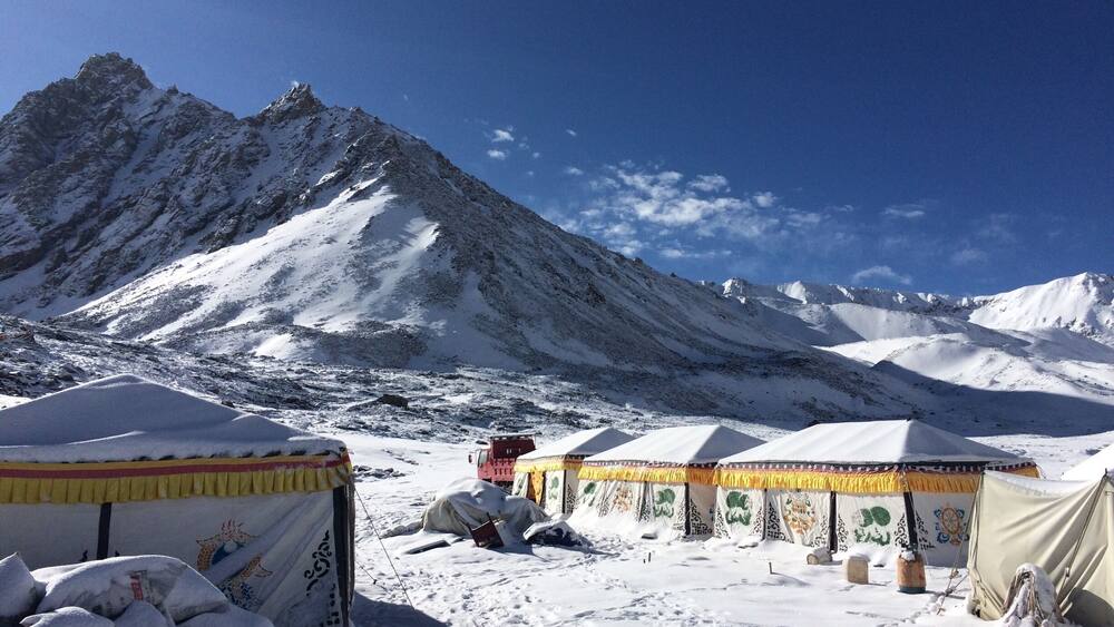 A snowy mountain landscape with tents and a clear blue sky.